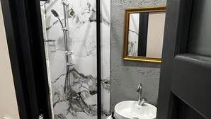 Un bagno con doccia, lavandino e specchio.