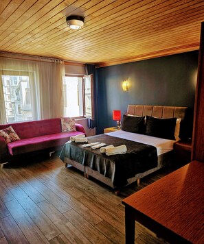 Habitación de hotel con cama, sofá y piso de madera.