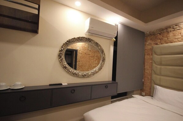Una habitación de hotel con una cama, un tocador con espejo y una pared de ladrillo.
