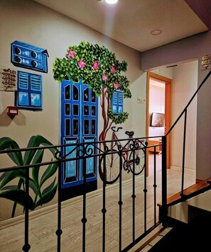 A staircase with a metal railing, a wall with a painted tree and windows, and a bicycle leaning against the wall. - Taxim 34 (Istanbul)