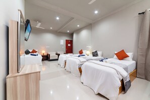 A hotel room with three beds, a flat-screen TV, a ceiling fan, and a red door. - Palm Oasis At Ukulhas (Ukulhas)
