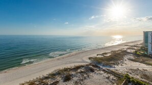 Ein Strand mit blauem Himmel, dem Meer und einem Gebäude rechts.