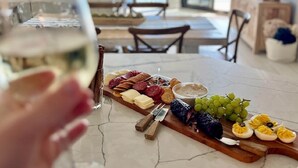 Ein Essbereich mit einem Marmortisch, gedeckt für eine Mahlzeit, mit einer Auswahl an Käse, Wurstwaren und Trauben.