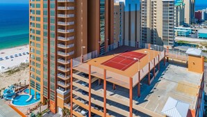 Ein Hochhaus-Hotel mit mehreren Etagen, einem Tennisplatz auf dem Dach und einem Poolbereich mit Wasserrutsche.