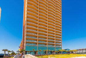 Un hôtel de grande hauteur doté de nombreux balcons, un ciel d’un bleu limpide et un drapeau.