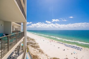A beach view from a balcony with lounge chairs, a pool, and umbrellas. - The Oasis 1405 Formerly Phoenix West Ii 1405 3 Bedroom Condo (Orange Beach)