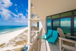 A balcony with a view of the beach, outdoor furniture, and a pool area. - The Oasis 1405 Formerly Phoenix West Ii 1405 3 Bedroom Condo (Orange Beach)