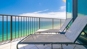 En balkon med to liggestole med udsigt over havet.