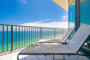 En balkon med to liggestole med udsigt over havet.