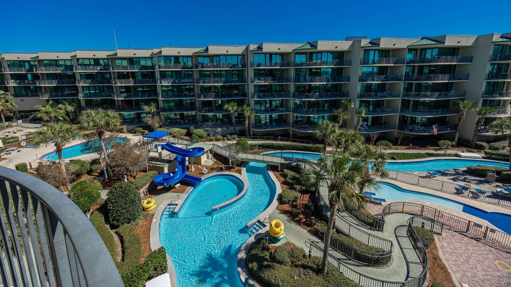 A hotel with multiple balconies, a swimming pool, and a water slide.