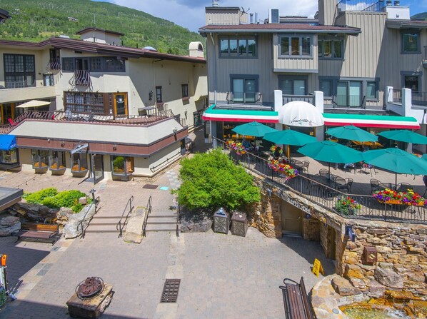 Une cour d’hôtel avec des espaces de repos en plein air, une fontaine en pierre et une vue sur les bâtiments environnants.