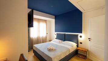 Un dormitorio moderno con una cama grande, una mesita de noche, un televisor montado en la pared y una puerta.