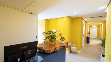Un comptoir d’accueil équipé d’un ordinateur, agrémenté de plantes en pot et d’un élément décoratif en bois.
