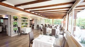 Un restaurante espacioso con vigas de madera, mesas blancas y una exhibición de vinos.