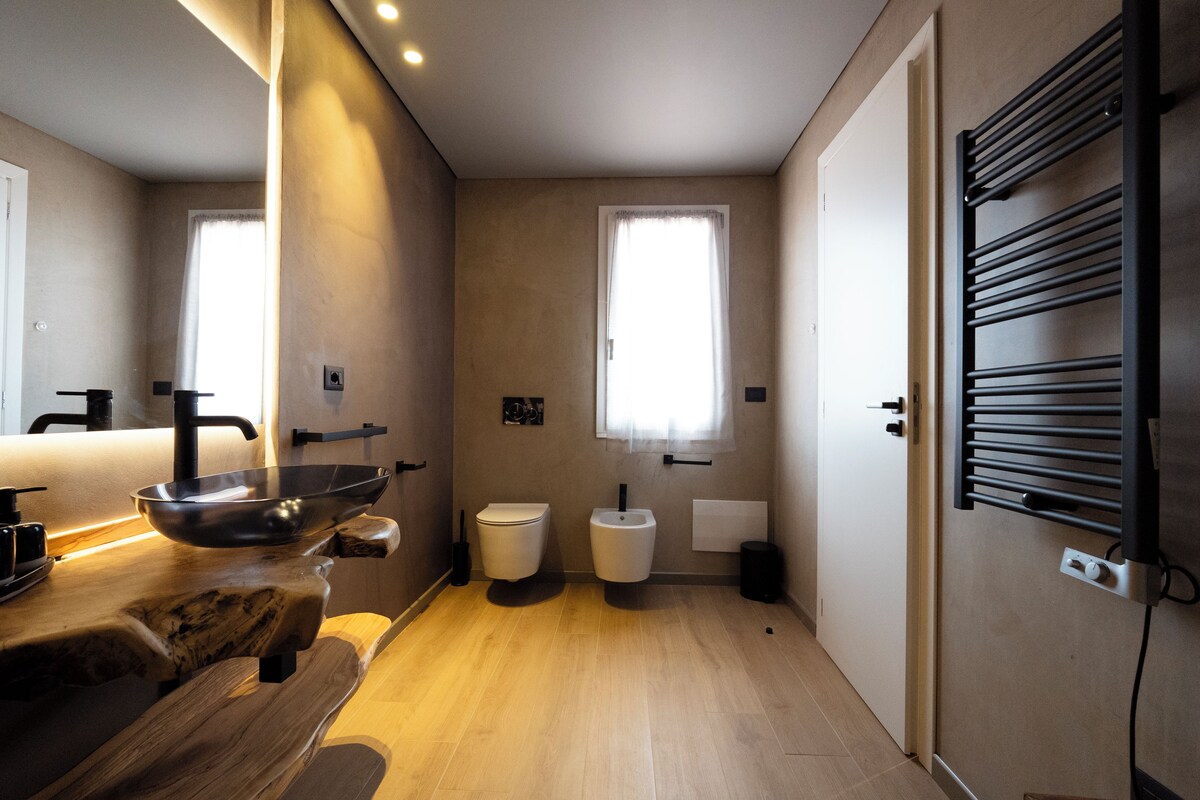 A modern bathroom with a wooden vanity, a sink, a toilet, and a bidet.