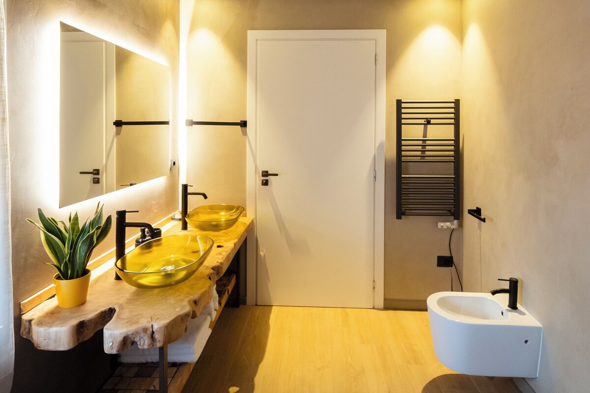 A modern bathroom with a wooden vanity, two sinks, a large mirror, and a towel rack.