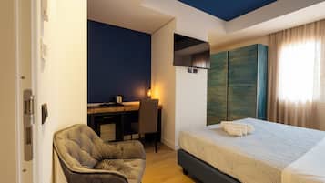 Une chambre d’hôtel avec un lit, un bureau, une chaise et une armoire.