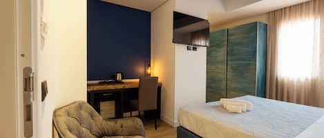 Una habitación de hotel con una cama, un escritorio, una silla y un armario.