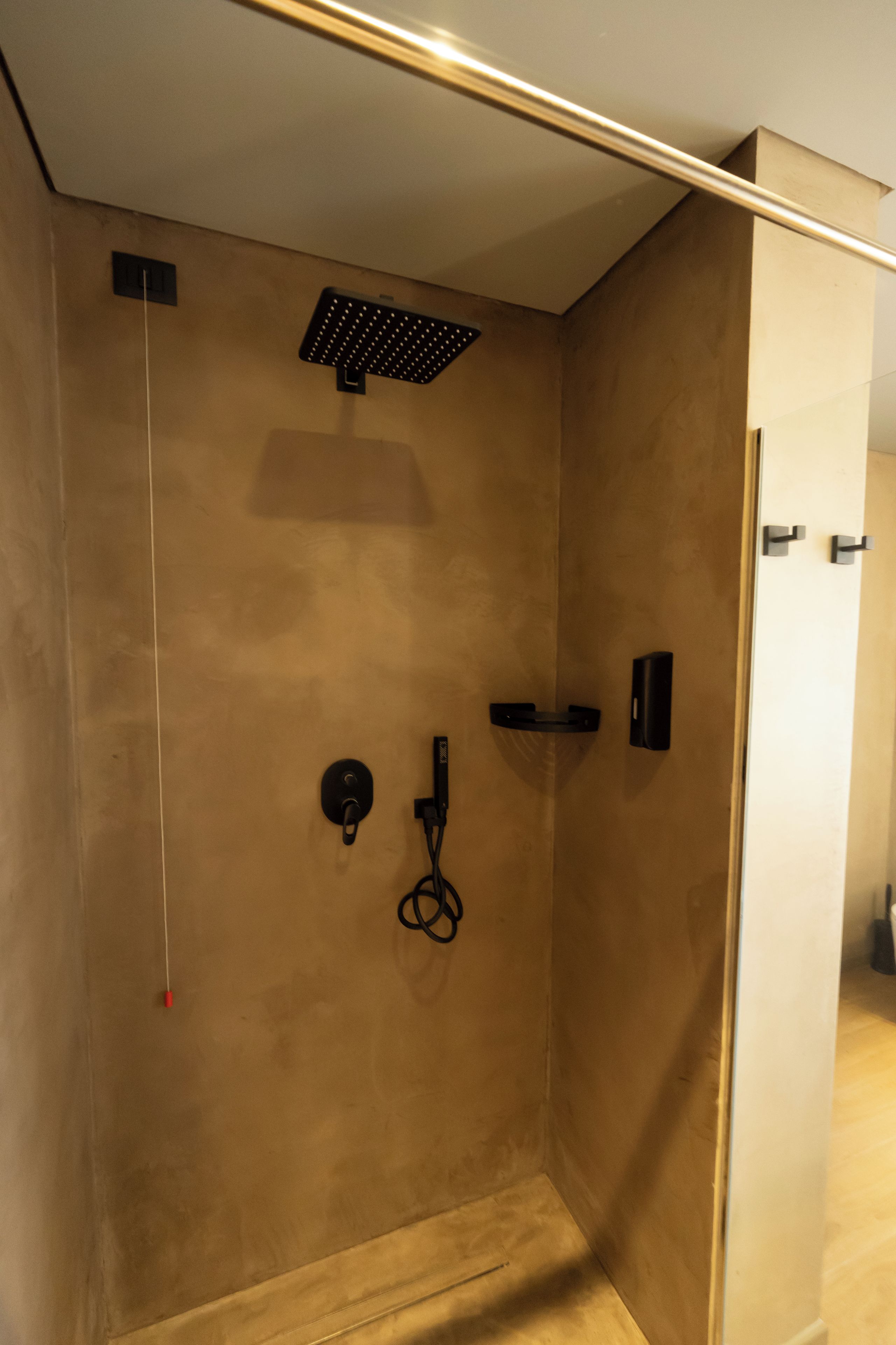 A modern shower with a control panel, a handheld showerhead, and a towel rack.