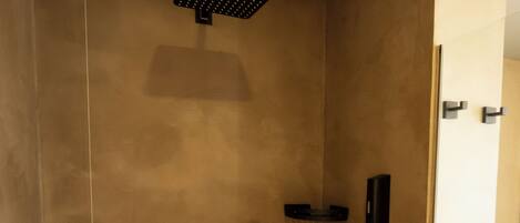 A modern shower with a control panel, a handheld showerhead, and a towel rack.