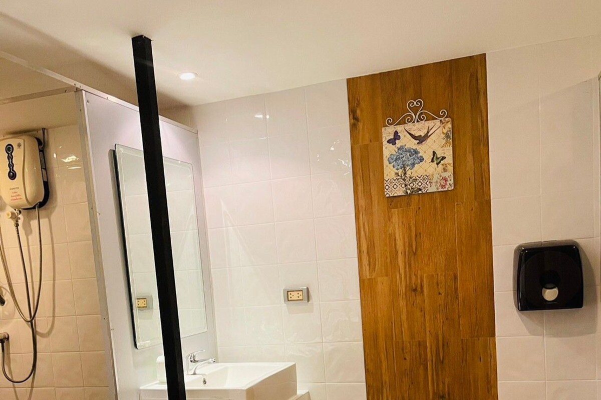 A bathroom with a white sink, a wooden door, a blue mat, and a hand dryer.