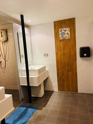A bathroom with a white sink, a wooden door, a blue mat, and a hand dryer. - Rabbitel Phuket (Phuket)