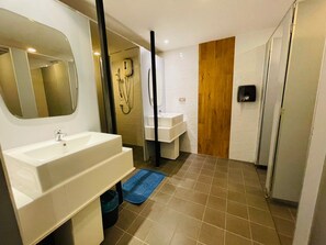 A modern bathroom with a large mirror, two sinks, a shower, and a wooden door. - Rabbitel Phuket (Phuket)