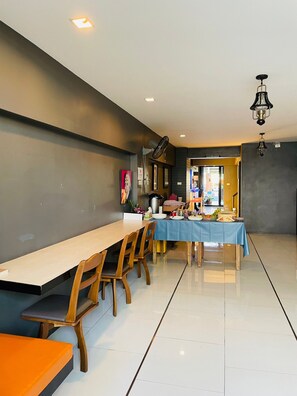 A dining area with a long wooden table, several chairs, and a blue tablecloth. There is a ceiling fan and pendant lights. - Rabbitel Phuket (Phuket)
