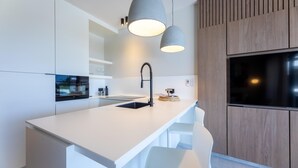 A modern kitchen with a white countertop, black faucet, and pendant lighting.