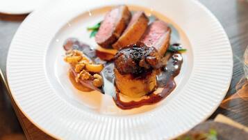A plate of food with a glass of red wine on a wooden table.