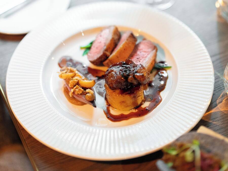 A plate of food with a glass of red wine on a wooden table.