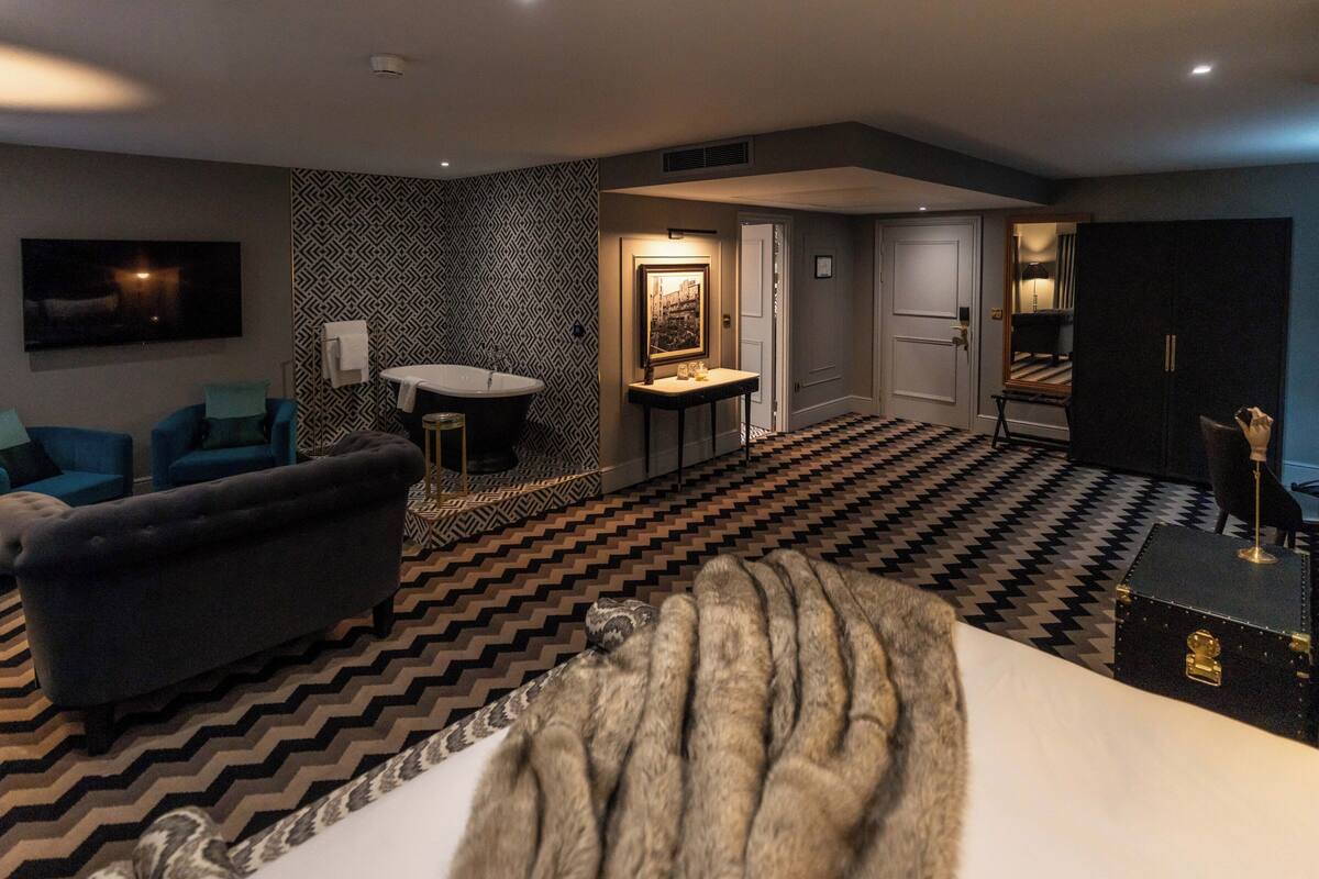 A modern living room with a patterned floor, a sofa, a small table, and a wall-mounted TV.