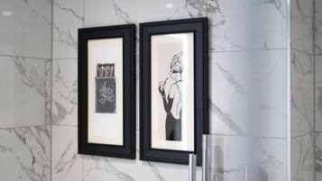 Two framed black and white artworks on a marble wall.