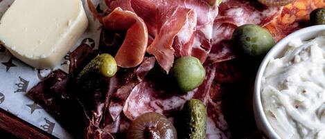 A charcuterie board with cheese, cured meats, olives, and pickles.