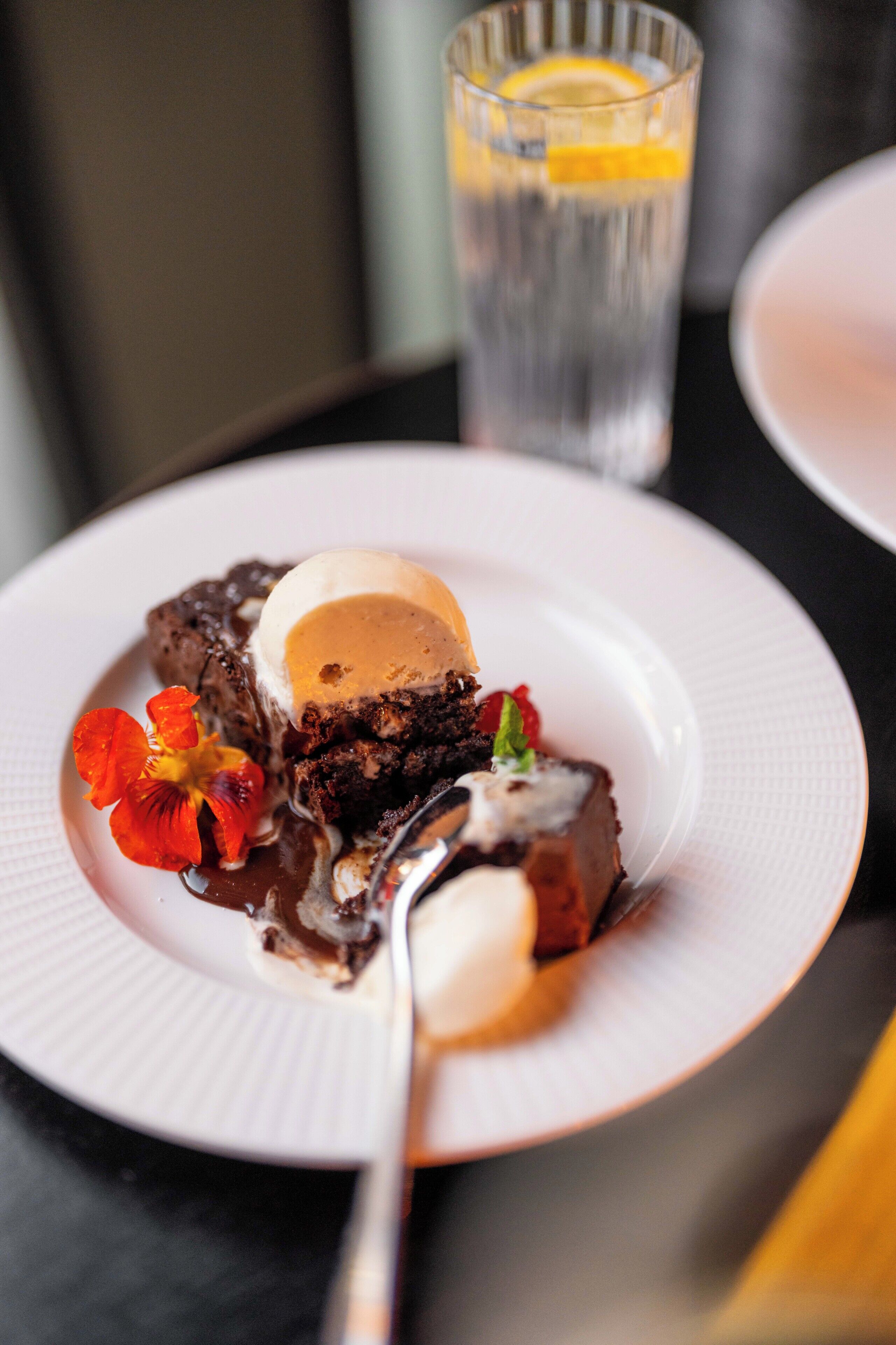 A dessert plate with a slice of cake, ice cream, and a flower garnish.