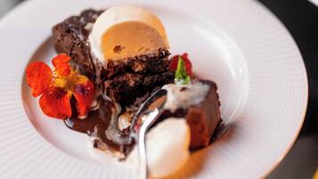 A dessert plate with a slice of cake, ice cream, and a flower garnish.