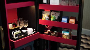 Zona de bar con una decoración en rojo y negro, que incluye una botella de vino, copas y diferentes aperitivos.