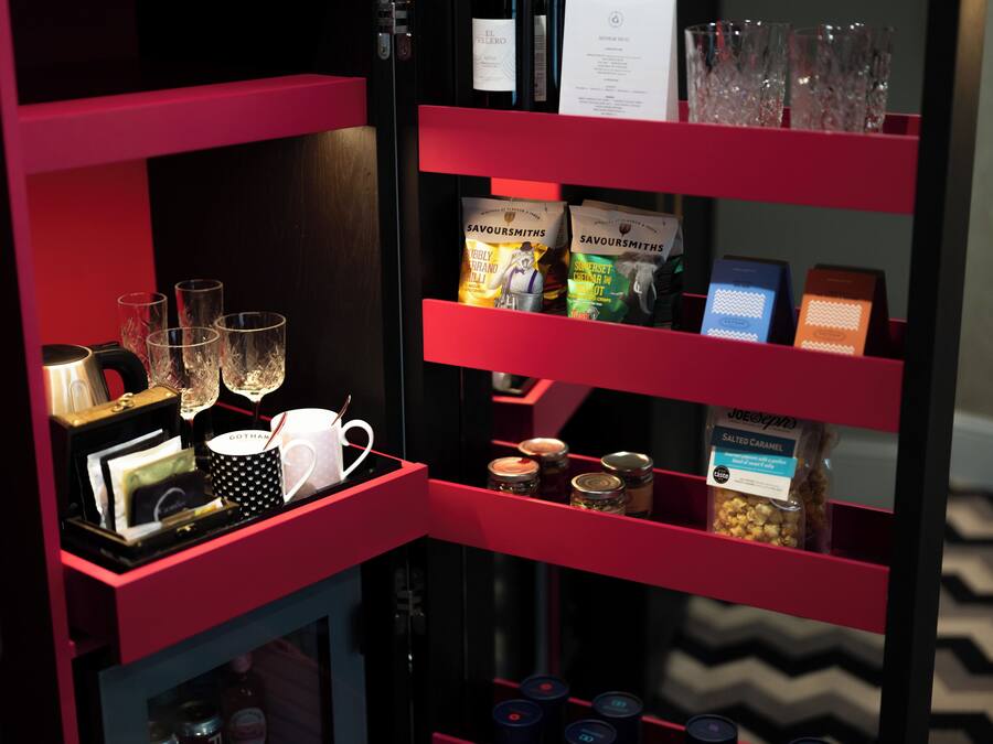 Zona de bar con una decoración en rojo y negro, que incluye una botella de vino, copas y diferentes aperitivos.