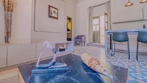 Ein modernes Wohnzimmer mit Marmorboden, einem blauen Sofa, einem Essbereich mit Tisch und Stühlen sowie einem großen Fenster mit Vorhängen.