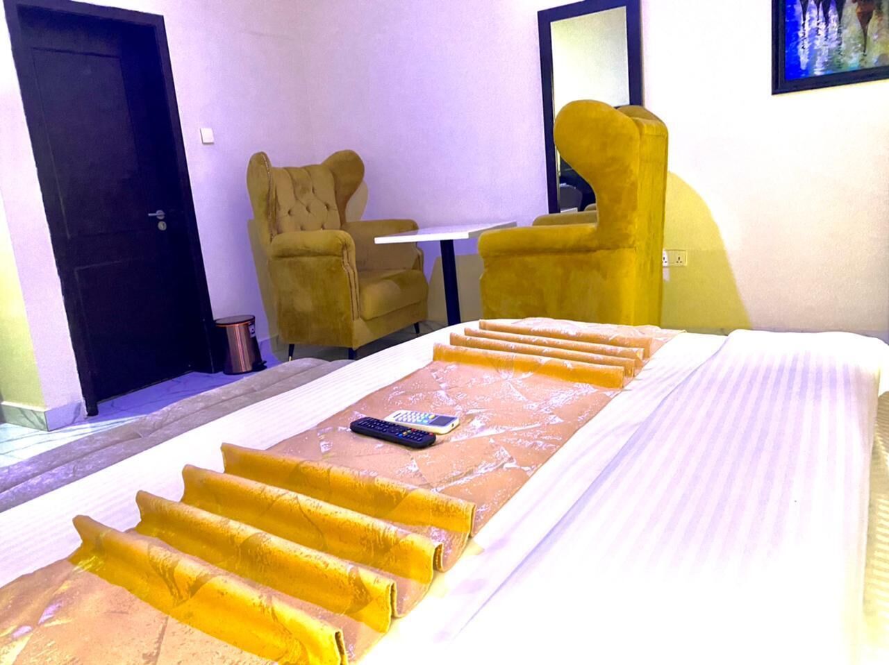 A hotel room with a bed, a remote control, and a chair.