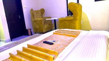A hotel room with a bed, a remote control, and a chair.