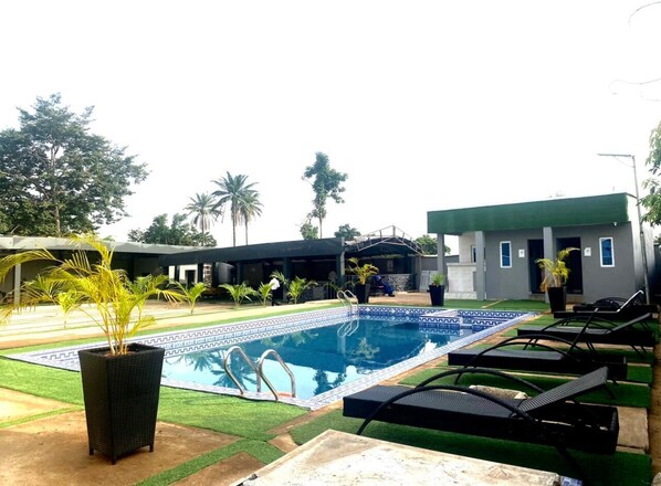 A swimming pool with lounge chairs and a small garden area. - Rove Luxury Hotel and Suites (Mgbakwu)