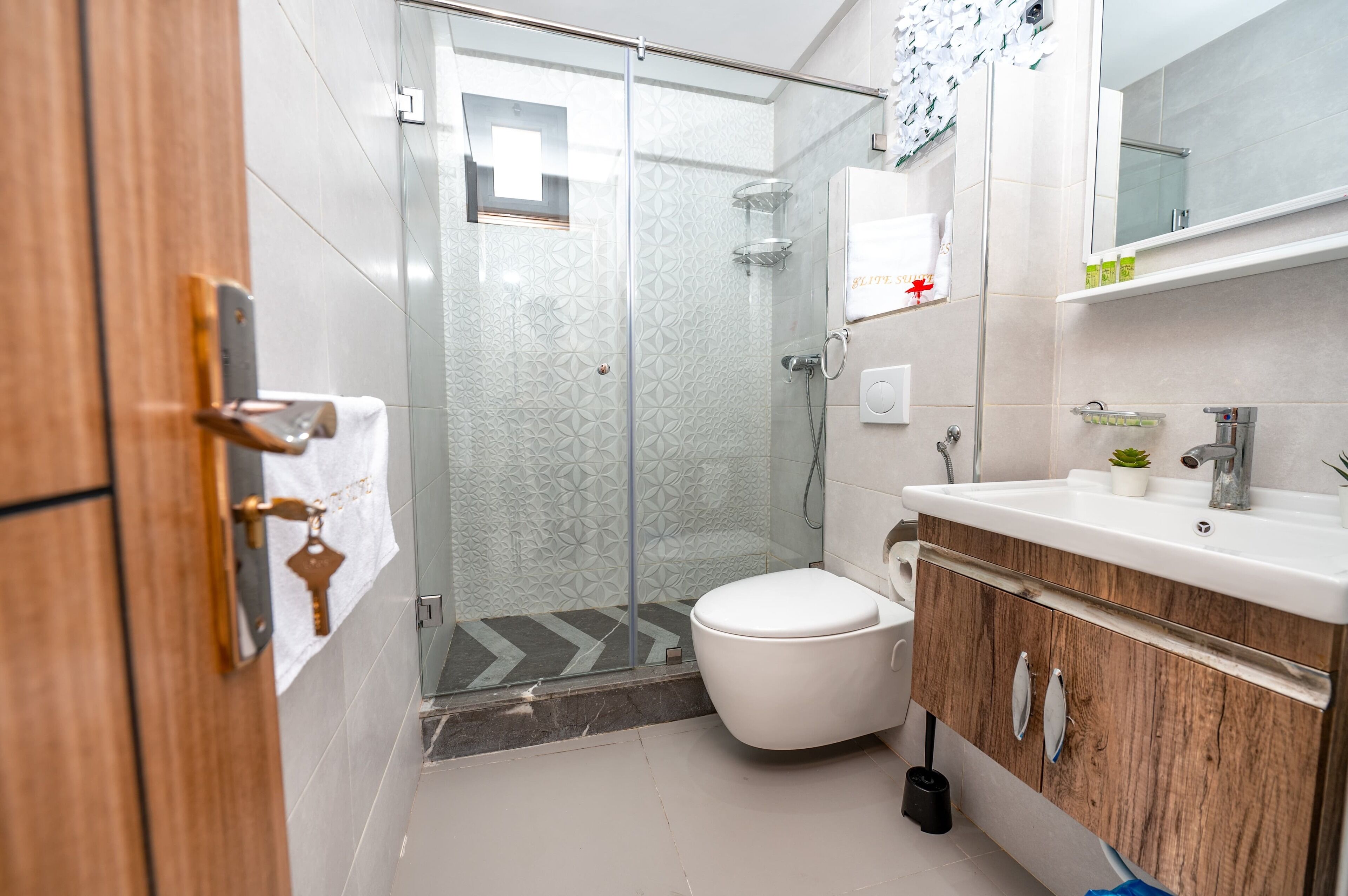 A modern bathroom with a glass shower enclosure, a white toilet, and a wooden vanity with a mirror.
