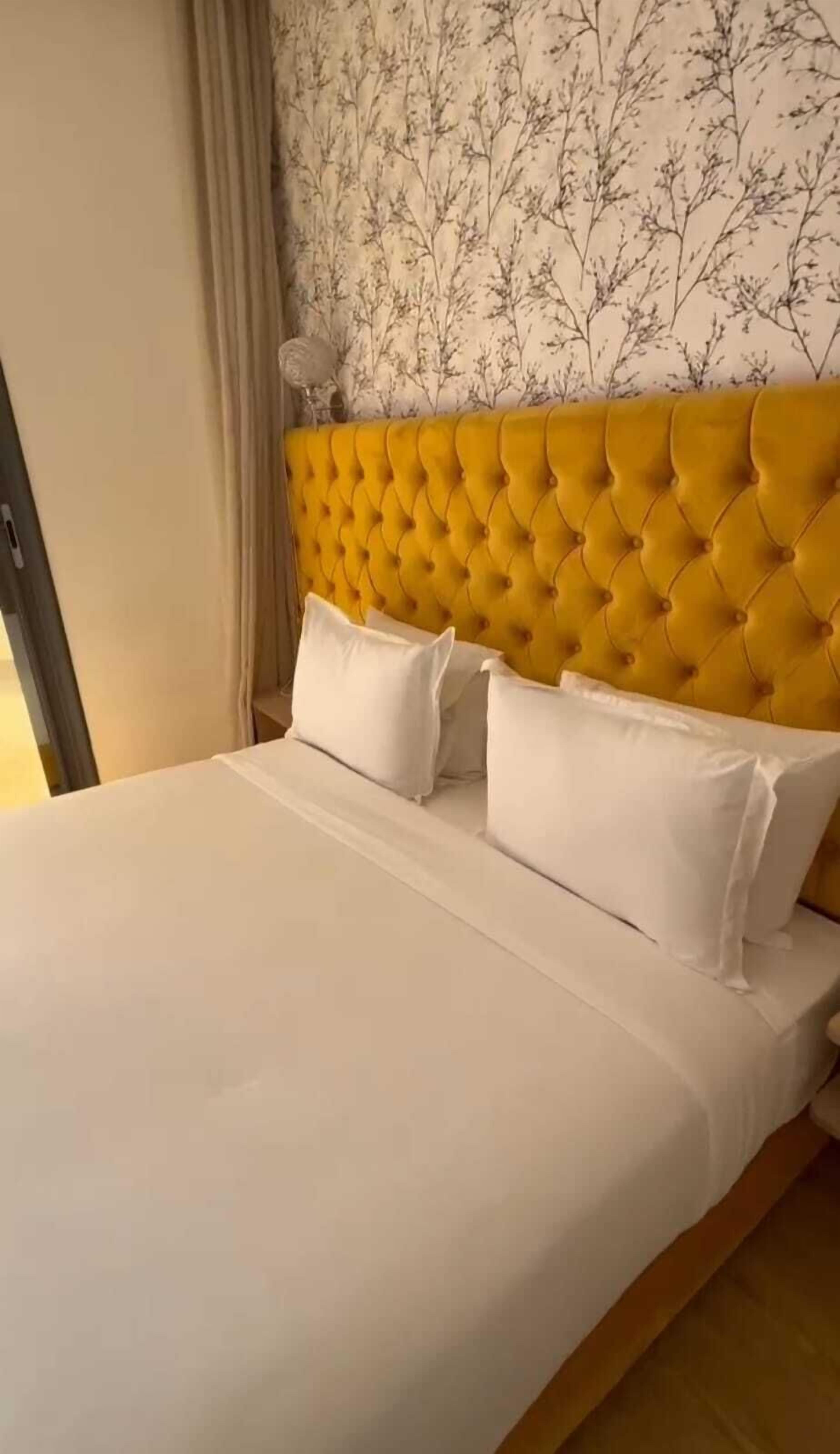 Ein Bett mit einem geblatteten Kopfteil, weißer Bettwäsche und zwei Kissen.