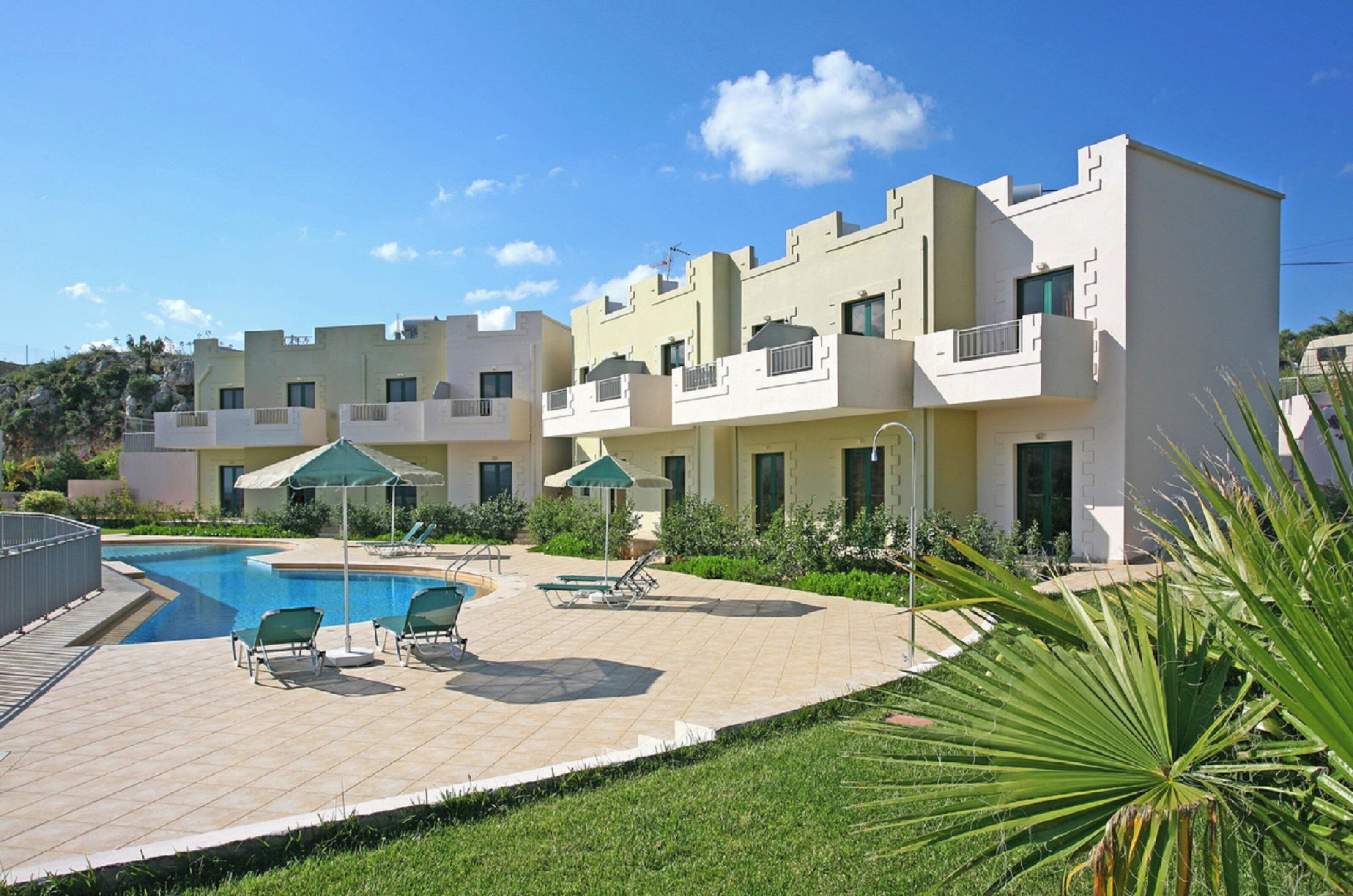 A modern hotel with a swimming pool, outdoor seating, and a well-maintained garden.