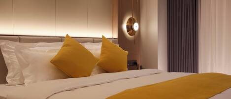 Een hotelkamer met een bed, wit beddengoed en een geel kussen.