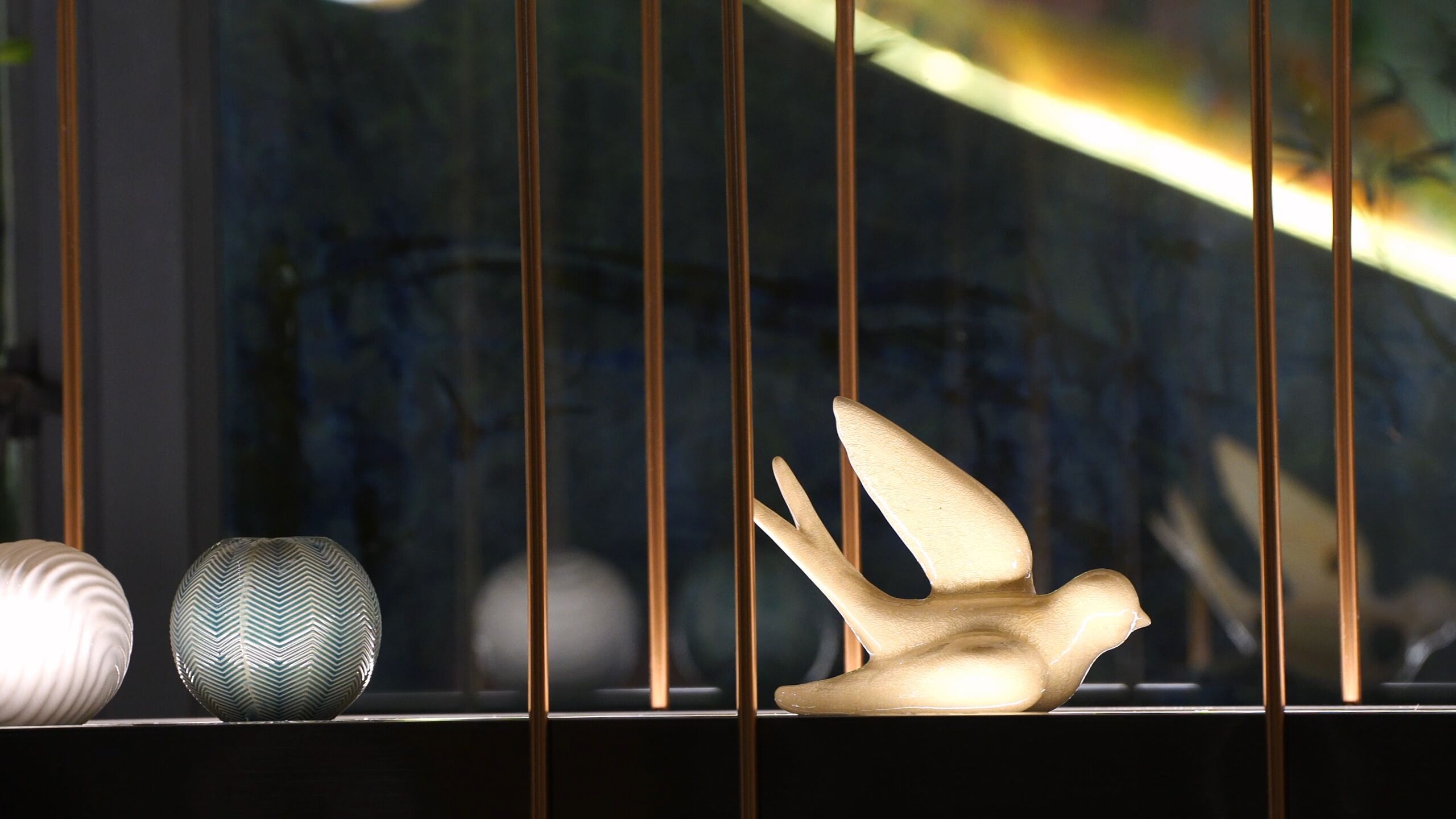 A window with vertical blinds, a decorative bird sculpture, and two patterned vases.