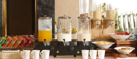 Un buffet de petit-déjeuner proposant une variété d’aliments, une machine à café et un assortiment de tasses.