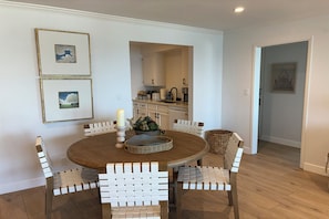 A dining area with a round table, white chairs, and a candle centerpiece.