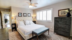 A bedroom with a bed, a bench, a dresser, a ceiling fan, and framed pictures on the wall. - SeaCliff - Seaclusion - Oceanfront Luxury in Santa Barbara (Santa Barbara)